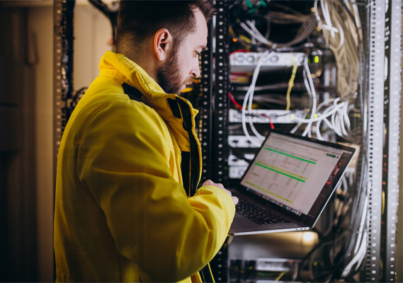Technician checking a network rack on a laptop