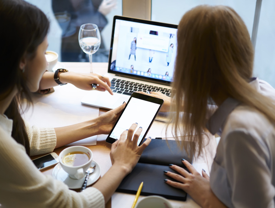Two people reviewing work on a laptop and tablet